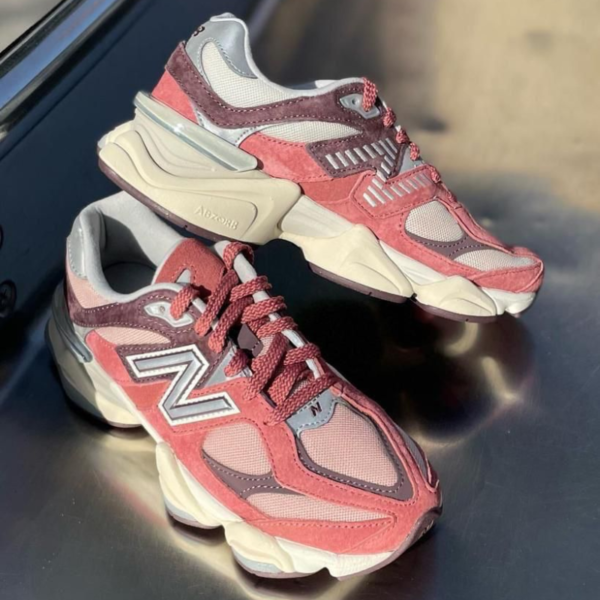 Pair of burgundy-pink New Balance sneakers with chunky beige soles, shown on a reflective surface.