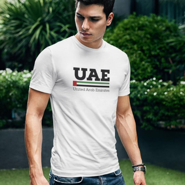 Untitleddesign_82_fdbbe2d5-5fcf-4472-ae5f-bc982db54af3 | UAE SPORT STORE Man wearing a white T-shirt with 'UAE United Arab Emirates' logo, standing outdoors with greenery in the background