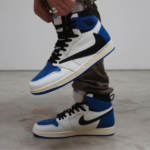 White, blue, and black high-top sneakers with a black Nike swoosh; foot lifted in mid-step, close-up.