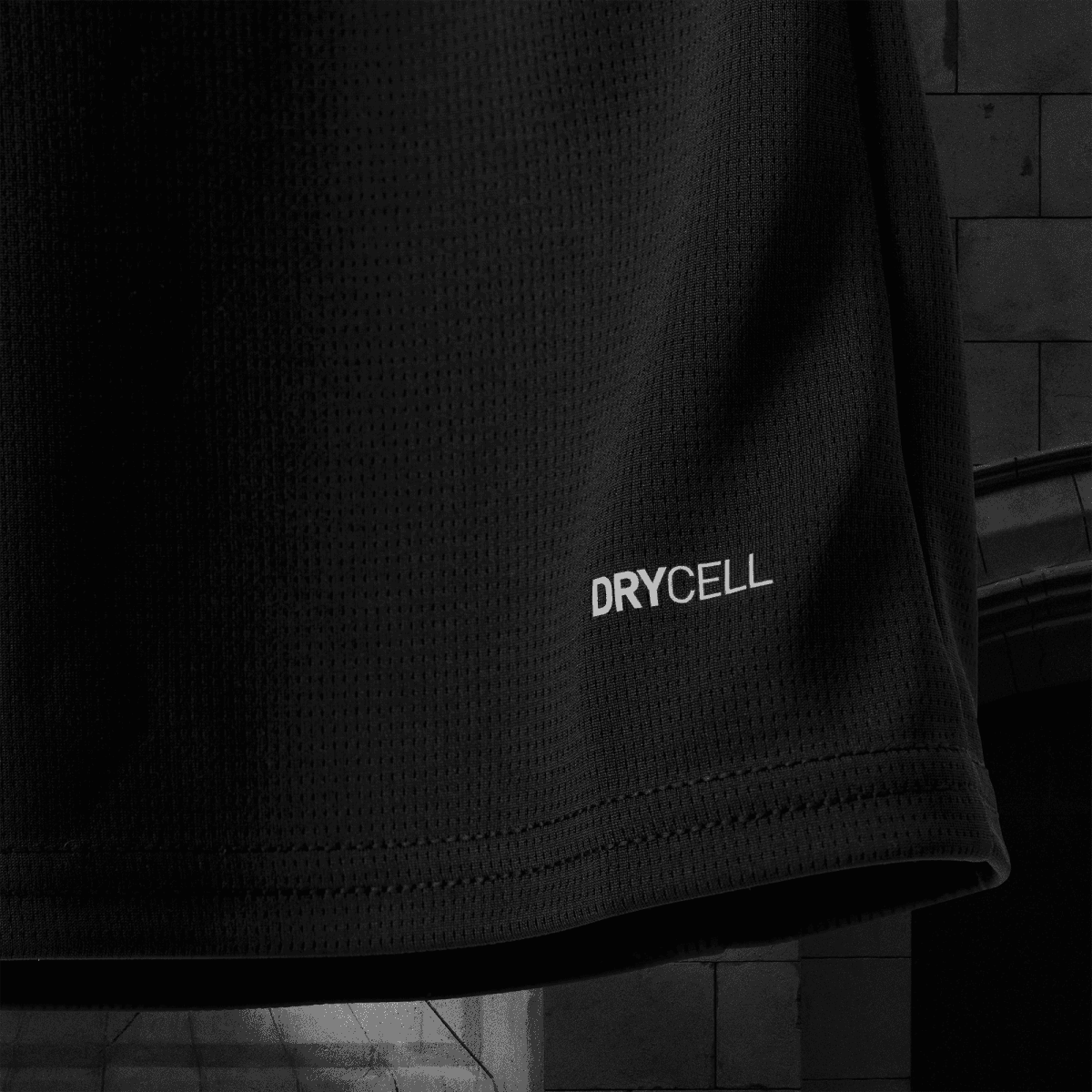 Close-up of black perforated fabric with the word DRYCELL printed near the bottom edge.