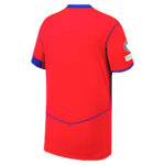 Back view of a bright red sports jersey with blue trim along the sleeves and hem, showing a simple design and a patch on the right sleeve