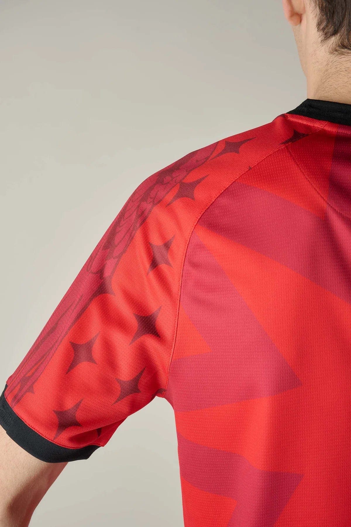VeneziaFCindossato-33 | UAE SPORT STORE Close-up of a red sports jersey sleeve with a black cuff and star pattern along the shoulder edge.