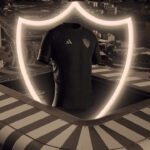VhSxYaak2XN0Zf_K | UAE SPORT STORE Black Adidas football jersey with a team crest, displayed inside a glowing shield outline against a cityscape backdrop.