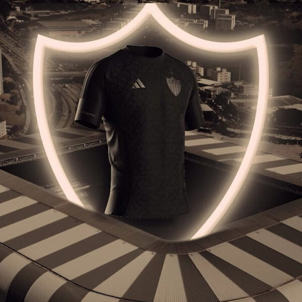 Black Adidas football jersey with a team crest, displayed inside a glowing shield outline against a cityscape backdrop.