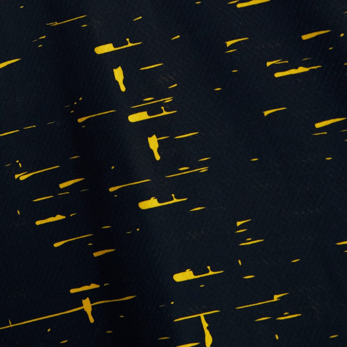 Abstract dark navy fabric with irregular yellow brush strokes scattered across the surface