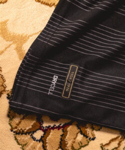 Close-up of dark striped fabric with a small gold-bordered label reading '1984 1994' and the brand name 'DRYCELL' in white letters on the left edge.