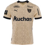 Beige RC Lens football jersey with black trim, team crest, and sponsors (Auchan, Nexans) plus Ligue 1 patch on sleeve.
