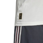 Close-up of white mesh jersey with Adidas Authentic Licensed Product tag, paired with navy shorts featuring white and red side stripes.