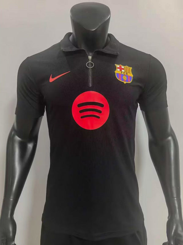 Black FC Barcelona polo shirt with Spotify sponsor logo on chest, Nike swoosh on the left, and club crest on the right; half-zip collar.
