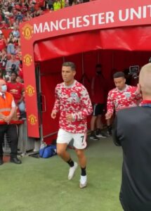 WhatsAppImage2021-10-02at12.29.44PM_06d0b3c7-b62f-4f82-bc85-ad69a15acb99 | UAE SPORT STORE Manchester United player in a red camouflage jersey runs out of the tunnel onto the pitch as fans look on in the stands.