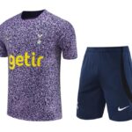 Tottenham Hotspur away kit: purple speckled jersey with yellow 'getir' sponsor and club crest, paired with navy shorts with white Nike swoosh.