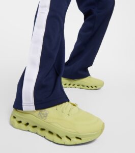 WhatsAppImage2024-07-22at18.36.42 | UAE SPORT STORE Close-up of lime-yellow athletic shoes with chunky, perforated sole paired with navy track pants featuring a white side stripe on a white background.
