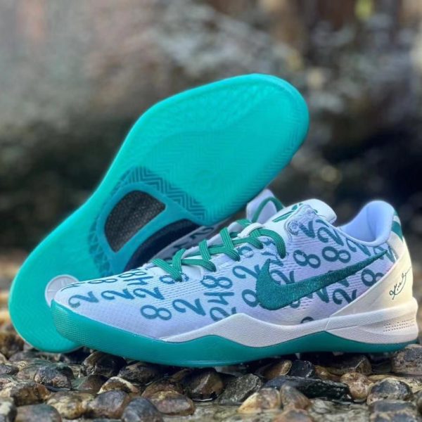 White running shoes with turquoise accents and a numeric pattern on the upper, placed on a rocky outdoor surface.