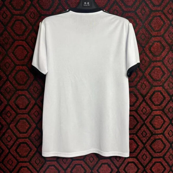 Back view of a plain white short-sleeve T-shirt hanging on a black hanger against a red geometric patterned background.