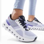 Light purple running shoes with black laces and a chunky white sole with circular cutouts, worn by a person in light leggings.] , but let's fix formatting.