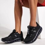 Person wearing black On-brand athletic sneakers with a distinctive hollow, pod-like sole.