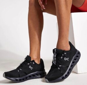 Person wearing black On-brand athletic sneakers with a distinctive hollow, pod-like sole.