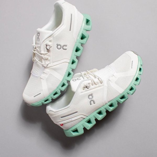 White running shoes with mint-green segmented outsole and side logo visible on gray background.