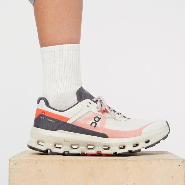 White and pink On running shoe on a wooden block, worn with a white crew sock.