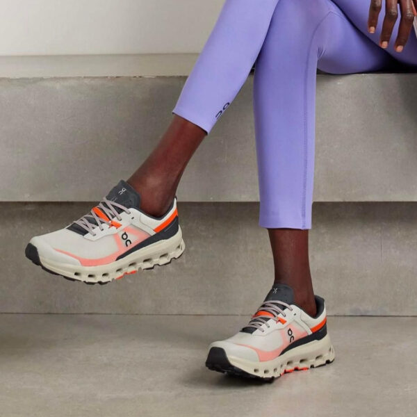 Person wearing lavender leggings and chunky white sneakers with orange accents, stepping with one foot on a concrete step.