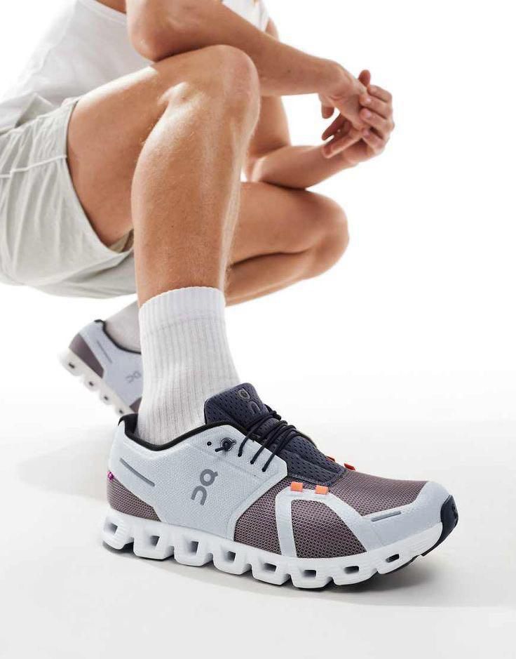 WhatsAppImage2025-05-13at17.05.50_1_53d60126-d913-4108-99e0-aee3671ce2f1 | UAE SPORT STORE Close-up of a blue-gray running shoe with a distinctive white chunked sole on a person crouching or kneeling, showing white socks and shorts.