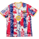 Colorful FC Barcelona jersey with red, blue, and white collage, crest, Nike swoosh, and gold trim at the neckline and sleeves.