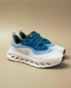 Pair of blue and white chunky-soled sneakers with black inner lining, angled view showing laces and side detailing.