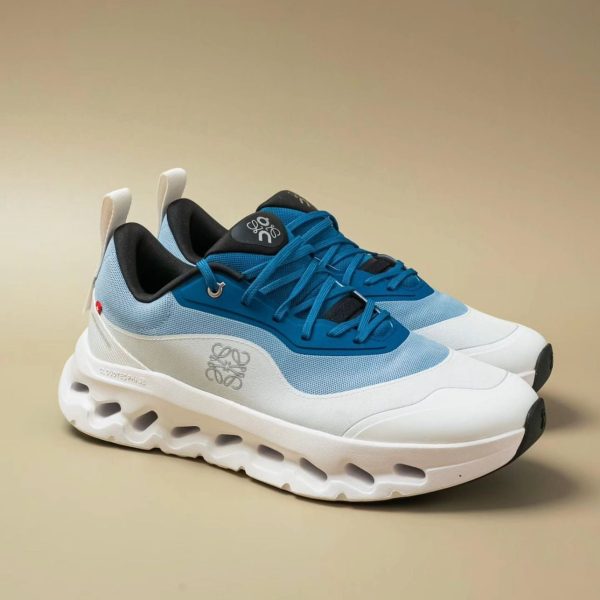 Pair of blue and white chunky-soled sneakers with black inner lining, angled view showing laces and side detailing.