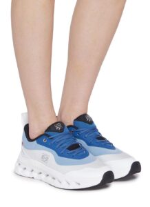 Close-up of legs and feet wearing blue and white chunky sneakers with a thick white sole.