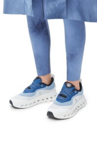 Person wearing blue sneakers and matching blue leggings, standing with feet apart against a white background