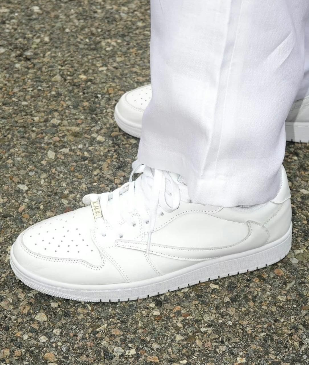 WhatsApp_Image_2024-07-21_at_10.54.49_1 | UAE SPORT STORE All-white sneakers with laces on a rough pavement, worn with white pants (side view).