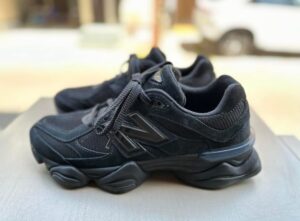 Black chunky-soled sneakers on a table outdoors, laces tied, with a blurred background.