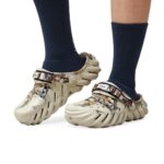 WhatsApp_Image_2024-09-06_at_09.18.51 | UAE SPORT STORE Camouflage-patterned Crocs-style clogs with adjustable heel strap, worn with dark navy socks on a white background.