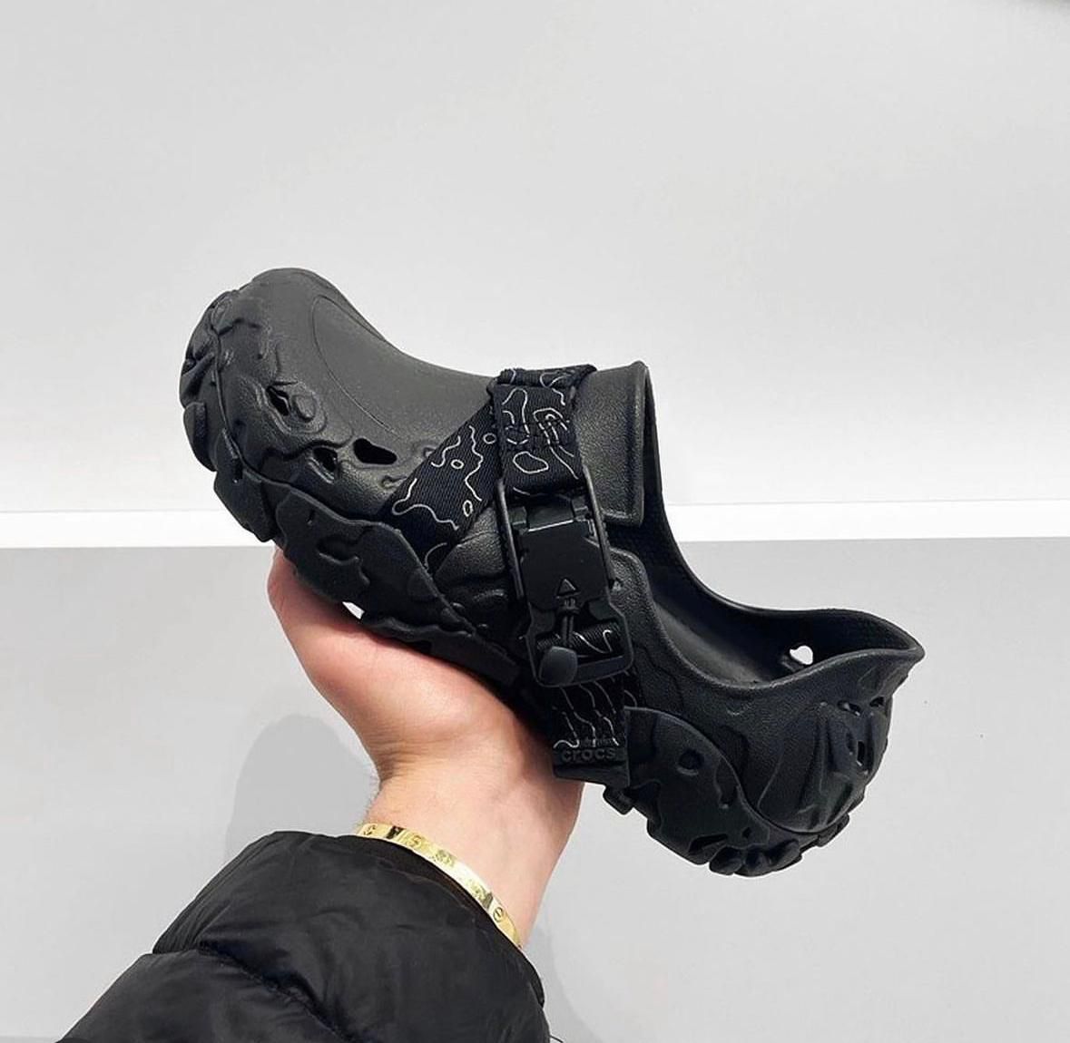 WhatsApp_Image_2024-09-07_at_09.58.11 | UAE SPORT STORE Black chunky slip-on clog with a patterned strap, held in a hand against a light background.