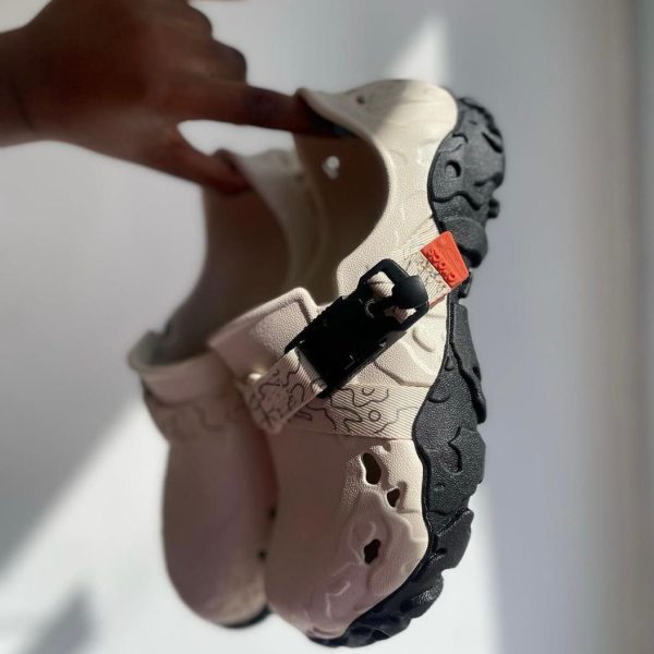 Beige sandal with a thick black traction sole and side buckle, shown from the side.