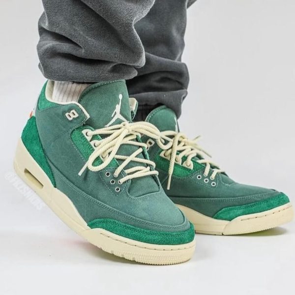 Green high-top sneakers with white laces and a cream sole, worn with gray sweatpants.