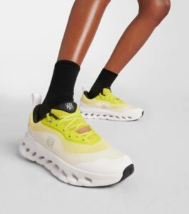 WhatsApp_Image_2024-09-09_at_09.47.28 | UAE SPORT STORE Close-up of a person wearing bright yellow athletic sneakers with chunky white soles, and black socks, shown from the side.
