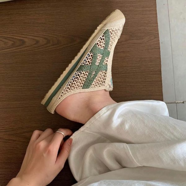 Beige crocheted slip-on sneaker on a bare foot, with light pants and a hand resting near the ankle.