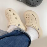 WhatsApp_Image_2024-10-19_at_11.33.53 | UAE SPORT STORE Beige Crocs-style clogs worn with white socks and cuffed jeans, photographed from above.