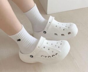 WhatsApp_Image_2024-10-19_at_11.33.55 | UAE SPORT STORE Person wearing white Crocs with white socks indoors on a light floor.