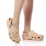 Peach-colored geometric clogs with back strap on a person’s feet.