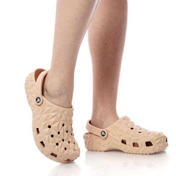 Peach-colored geometric clogs with back strap on a person’s feet.