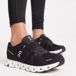 Black On-brand running shoes with a white segmented sole worn over black leggings on a light background