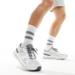 Person wearing white and gray running shoes with striped socks, mid-stride, on a white background