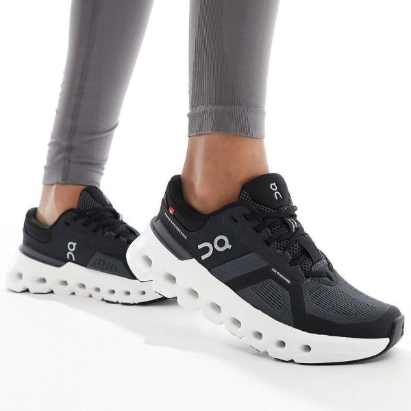 Black On Running sneakers with a chunky white sole, worn with gray leggings by a person standing.
