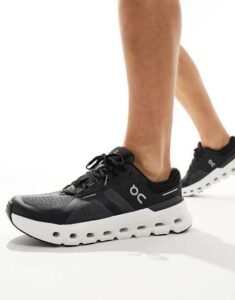 Person wearing black On running sneakers with a white thick sole, mid-step forward.