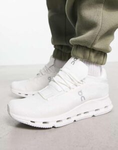 WhatsApp_Image_2024-11-06_at_10.52.35 | UAE SPORT STORE Close-up of white running shoes with laces, worn with olive joggers on a light floor.