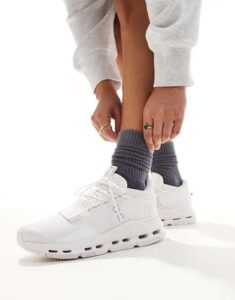 WhatsApp_Image_2024-11-06_at_10.52.38 | UAE SPORT STORE Person tying white athletic sneakers while wearing dark gray socks, close-up of lower legs.
