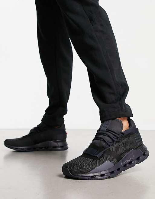 Close-up of black running shoes with a chunky sole, worn with black joggers, as the person takes a step forward.