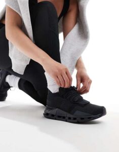 WhatsApp_Image_2024-11-06_at_11.22.32 | UAE SPORT STORE Person kneeling and tying black athletic sneakers, wearing white socks and a gray hoodie.